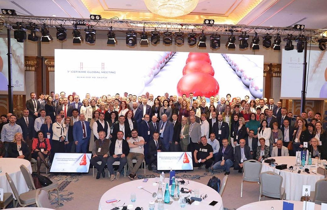 Group photo of a large business or conference audience seated at round tables in a hotel ballroom, taken from the front of the room facing the crowd.