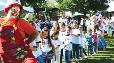 Entertainer performing for children at an outdoor Alkaloid event