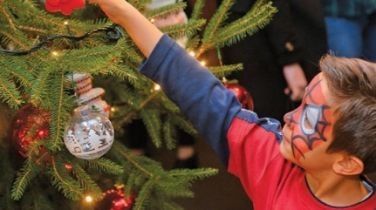 Child hanging a bauble on a Christmas tree
