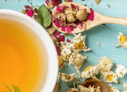 Cup of herbal tea surrounded by dried chamomile flowers