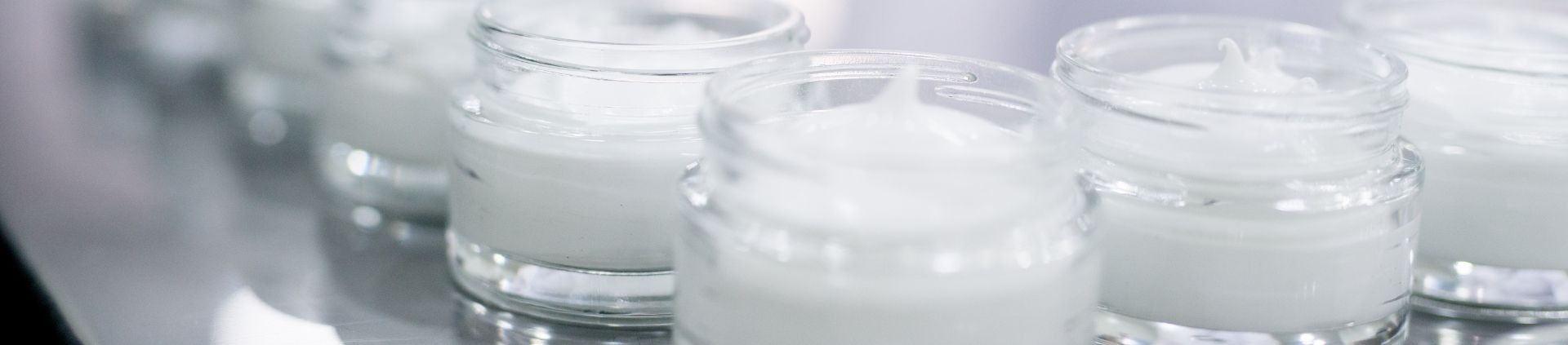 Rows of white cosmetic cream jars on a production line
