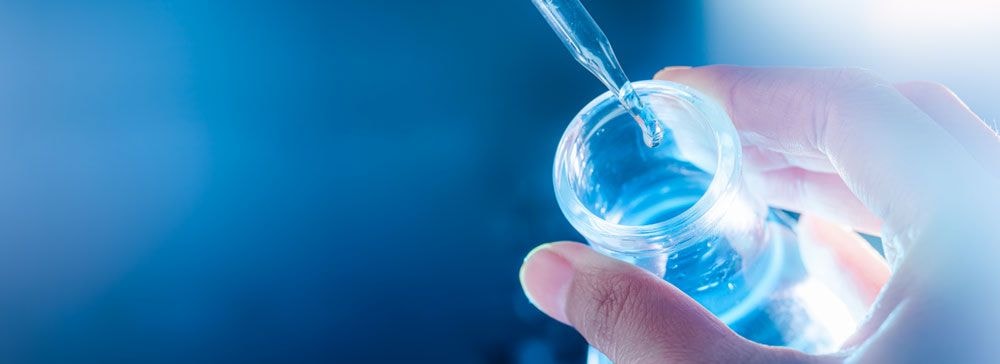 Drop of blue liquid falling into a laboratory jar