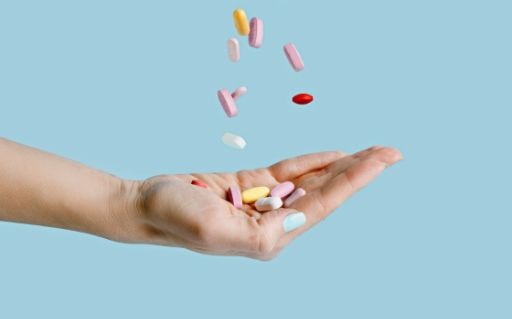 Open hand holding assorted tablets and capsules