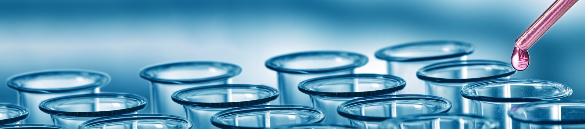 Pipette dispensing a red sample into a row of glass test tubes