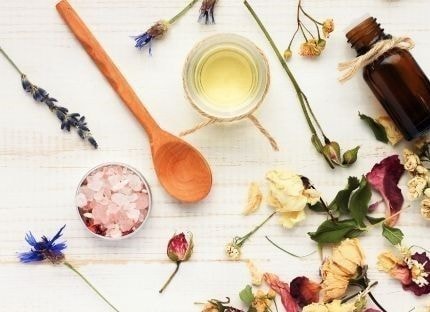 Dried lavender, herbs and a wooden spoon arranged on a white surface
